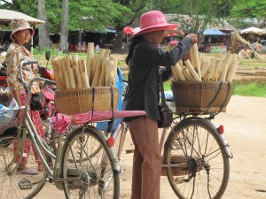 Vendor with bamboo tubes of krahlan in basket Vendor with bamboo tubes of krahlan in basket